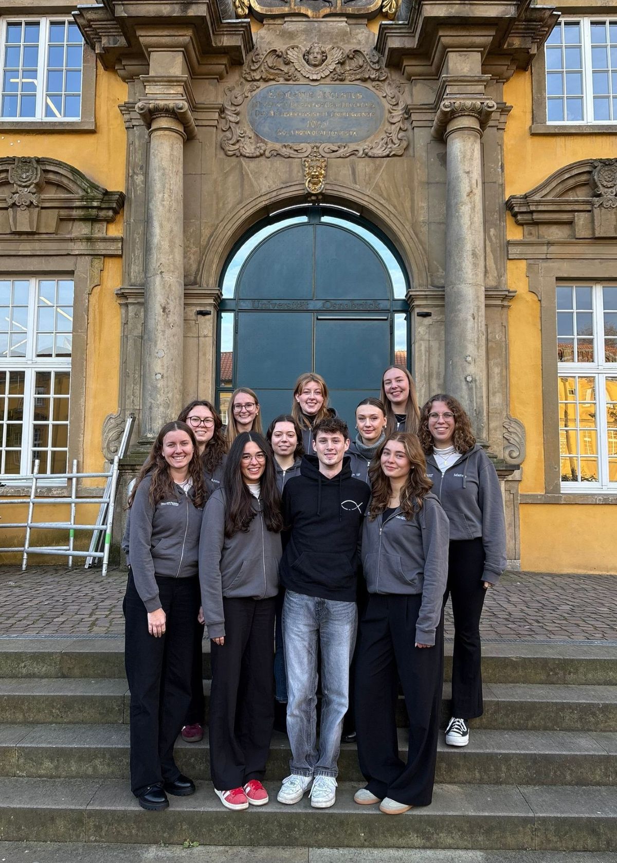 Die Studierenden der Fachschaft stehen auf der Schlosstreppe und lächeln in die Kamera